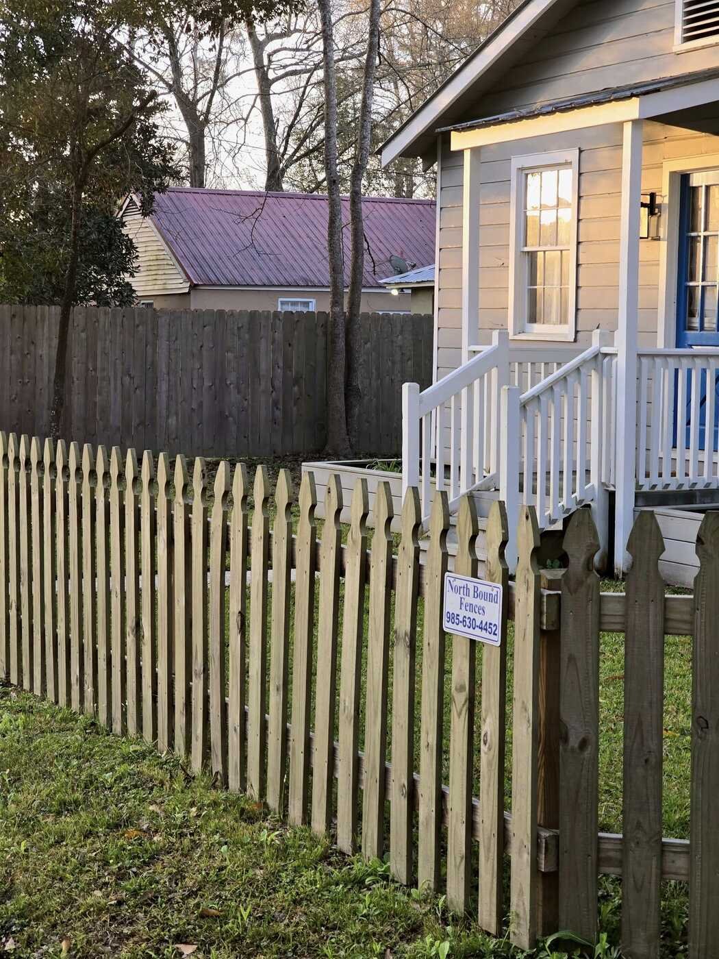 Wood picket fence built by Northbound Fences with the company sign on the gate